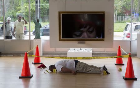 Two men look through a window at an art installation depicting the body of Michael Brown, made by artist Ti-Rock Moore, at Gallery Guichard in Chicago, Illinois, July 14, 2015. REUTERS/Andrew Nelles