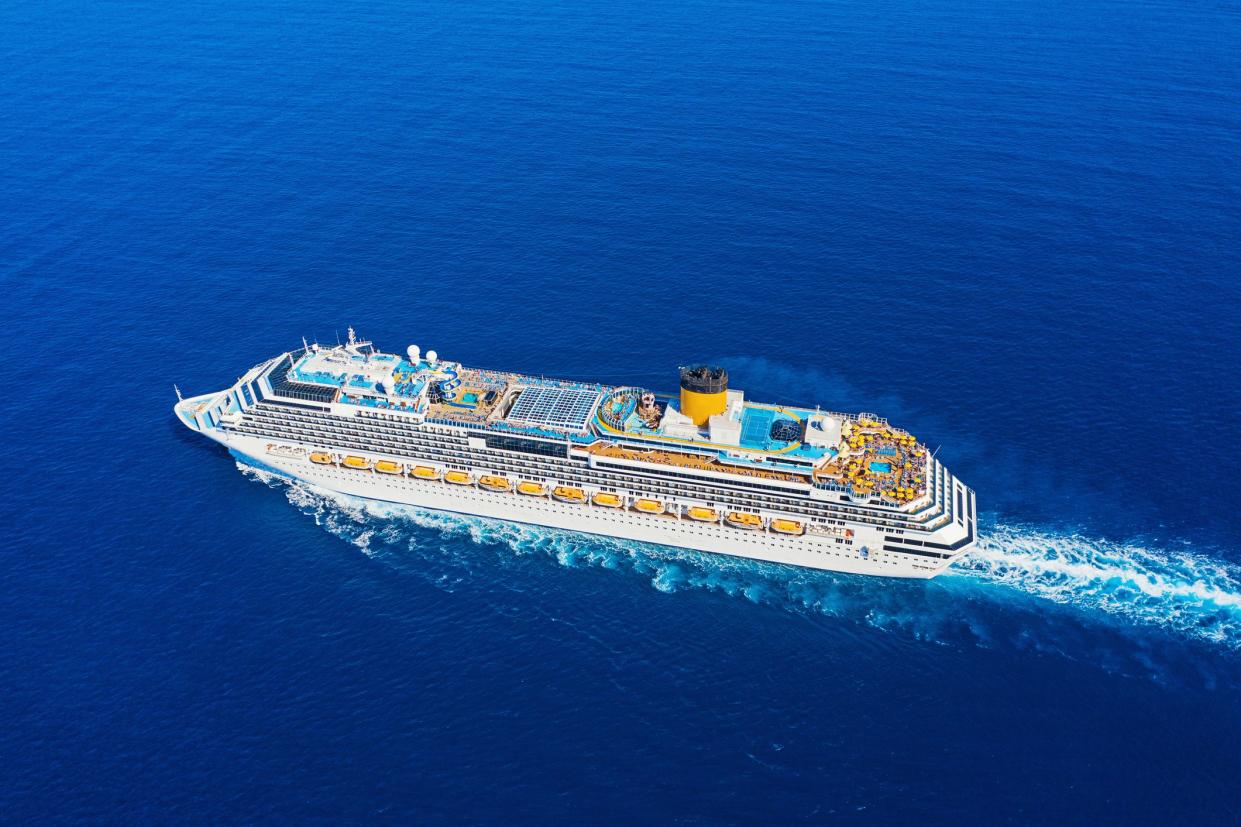 Aerial view of modern large white cruise ship liner with colorful deck against clear blue sea. Top view from drone of floating passenger liner: Valletta, Malta - May 8, 2019