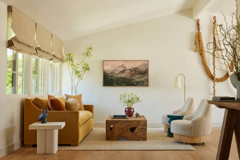 Yellow velvet couch, sculptural wood coffee table, white marble side table, white boucle accent chairs