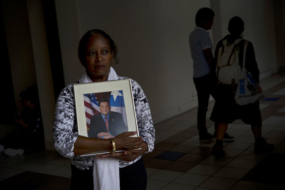 In this Sept. 4, 2018 photo, Gloria Rosado Ortiz poses with an image of her late husband Ernesto Curiel in San Juan, Puerto Rico. Curiel, a 60-year-old who had heart problems and diabetes, walked 10 flights of stairs to the ground floor of his condominium, twice a day, to get insulin from a refrigerator cooled by a generator after Hurricane Maria hit. On Oct. 29, he died of a heart attack. Rosado applied to FEMA in Nov. 2017 for financial aid to defray $4,000 in funeral costs, and was told it was going to take some time due to the large number of applications following the rise in the official death toll. “He was in a fragile state, but not so fragile that he’d only last a month after the hurricane,” said Ortiz. (AP Photo/Ramon Espinosa)