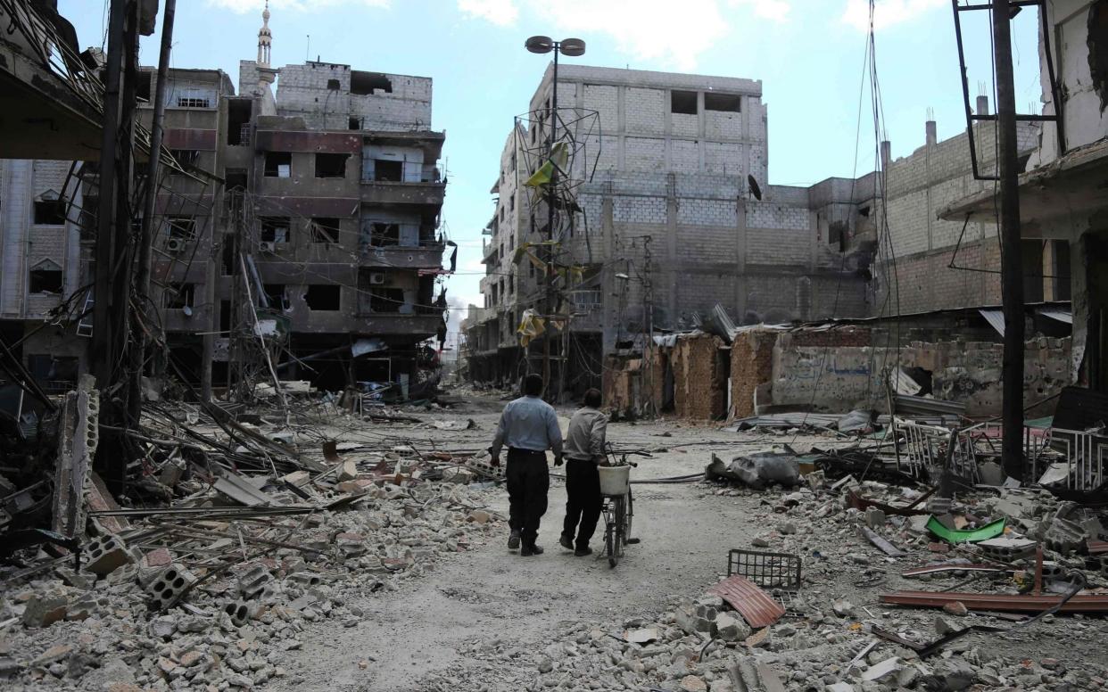 Syrians walk along a destroyed street in the rebel-held town of Arbin in Eastern Ghouta  - AFP