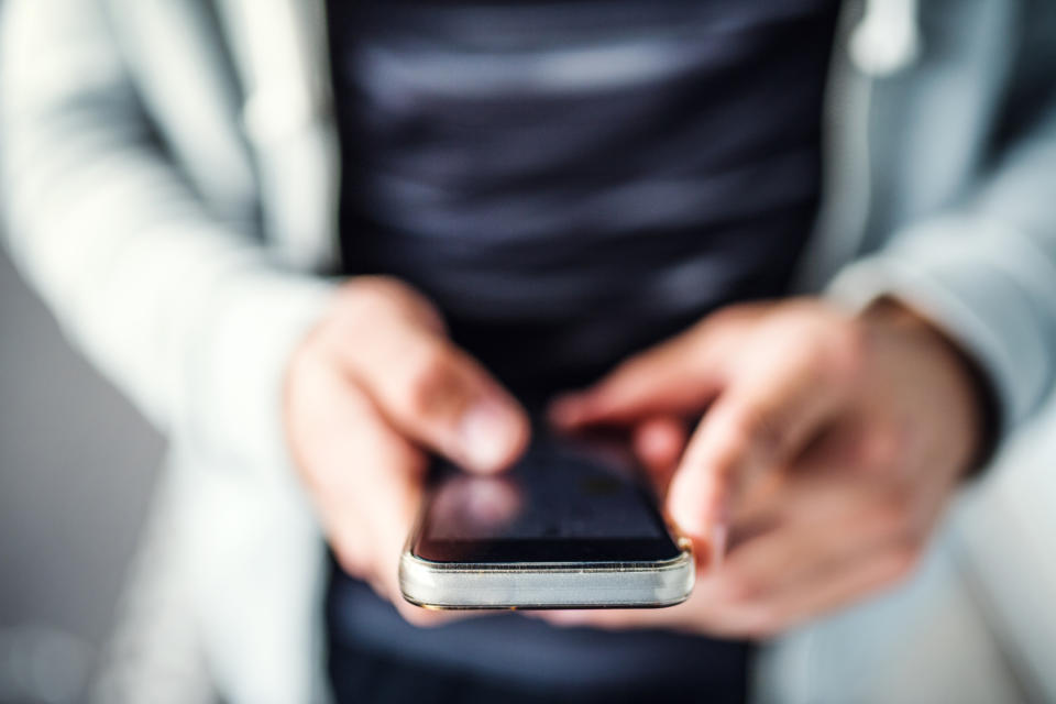 Hands of guy using phone.