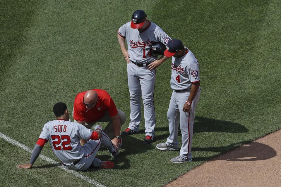 Washington Nationals' Bob Henley (14) and Dave Martinez (4) watch as a trainer checks on Juan Soto (22) after Soto was injured during the seventh inning of a baseball game against the New York Mets, Sunday, Aug. 11, 2019, in New York. (AP Photo/Frank Franklin II)