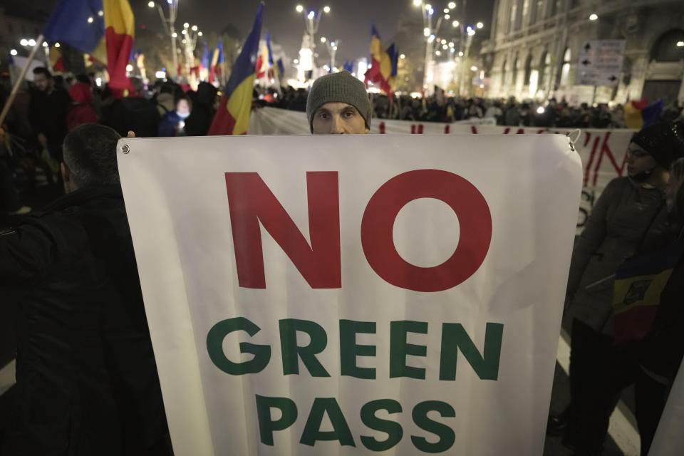 FILE - A man holds a banner during a protest against vaccinations, the introduction of the green pass and COVID-19 related restrictions in Bucharest, Romania, Sunday, Nov. 7, 2021. This was supposed to be the Christmas in Europe where family and friends could once again embrace holiday festivities and one another. Instead, the continent is the global epicenter of the COVID-19 pandemic as cases soar to record levels in many countries. With infections spiking again despite nearly two years of restrictions, the health crisis increasingly is pitting citizen against citizen — the vaccinated against the unvaccinated. (AP Photo/Vadim Ghirda, File)