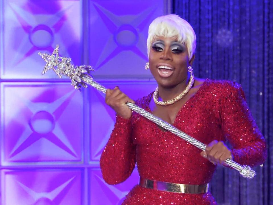 Monet X Change in red jumpsuit holding a septor on drag race