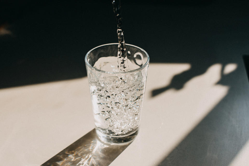 Water being poured into a glass from above