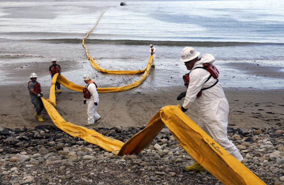 FILE - In this May 21, 2015, file photo, workers prepare an oil containment boom at Refugio State Beach, north of Goleta, Calif., two days after an oil pipeline ruptured, polluting beaches and killing hundreds of birds and marine mammals. A proposal to replace a pipeline near Santa Barbara that was shut down in 2015 after causing California's worst coastal oil spill in 25 years is inching through a government review, even as the state moves toward banning gas-powered vehicles and oil drilling. (AP Photo/Jae C. Hong, File)