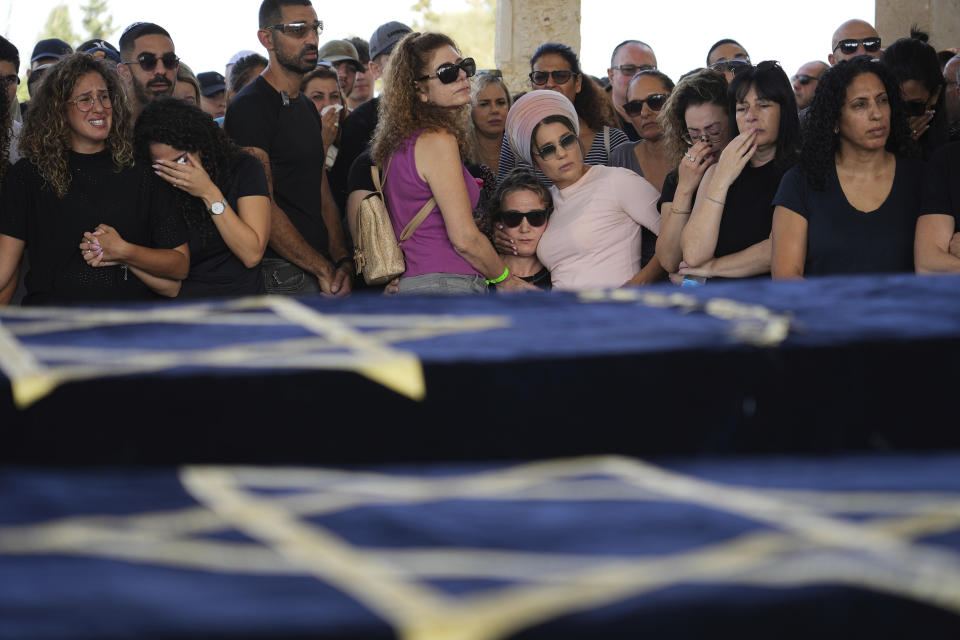Mourners gather around the coffins of Gil Taasa and his son Or, during their funeral in Kibbutz Nitzan, Israel, Wednesday, Oct. 18, 2023. The Father and his son were killed by Hamas militants on Oct. 7 in Netiv Haasara, close to the Gaza Strip's separation fence with Israel, as the militant Hamas rulers of the territory carried out an unprecedented, multi-front attack that killed over 1,400 and captured many Israelis. (AP Photo/Tsafrir Abayov)