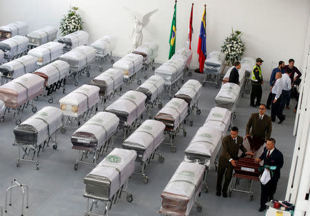 Funeral workers walk next to coffins holding the remains of the victims who died in the accident of the plane that crashed into the Colombian jungle with Brazilian soccer team Chapecoense onboard, in Medellin, Colombia December 2, 2016. REUTERS/Jaime Saldarriaga