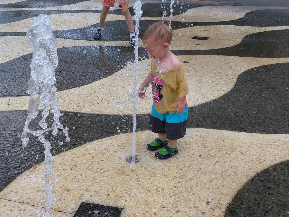 toddler playing in the water at a splash pad in universal studios citywalk area