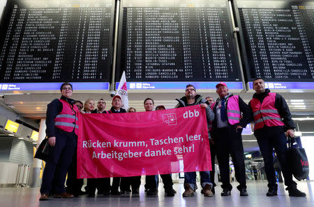 Union members with a banner reading "back broken, pockets empty, thanks a lot employer" pose for a picture during a strike over higher wages at Germany's largest airport in Frankfurt, Germany, January 15, 2019. REUTERS/ Kai Pfaffenbach