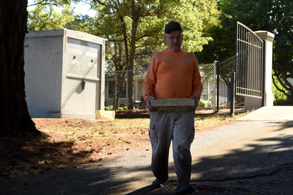 Mick Hersey moves a piece of sandstone block from the grave site of Benjamin and Angie Harrison, at left, at Bremerton's Ivy Green Cemetery.