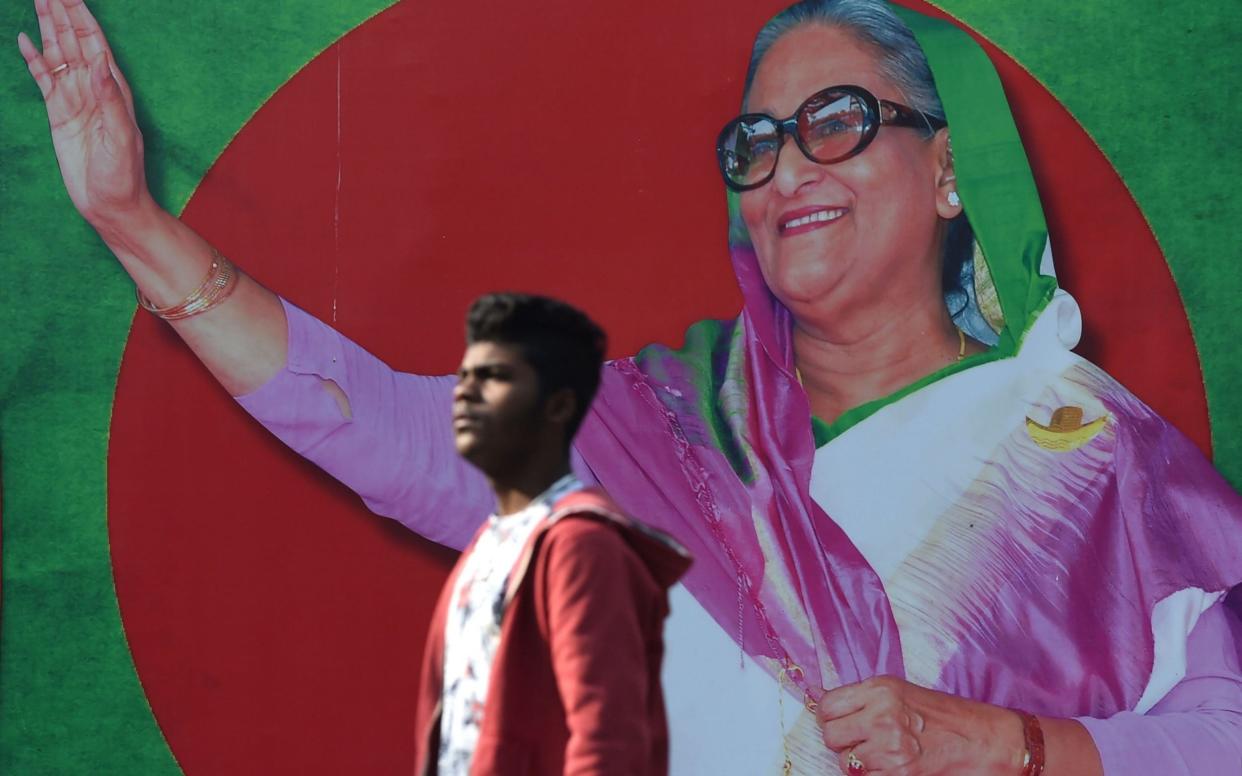 A Bangladeshi man walks past a photo of Prime Minister Sheikh Hasina, in Dhaka on December 29, 2018 - AFP