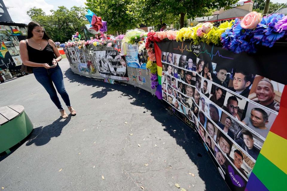 PHOTO: In this June 11, 2021, file photo, a visitor looks over a display with the photos and names of the 49 victims that died at the Pulse nightclub memorial in Orlando, Fla. (John Raoux/AP, FILE)