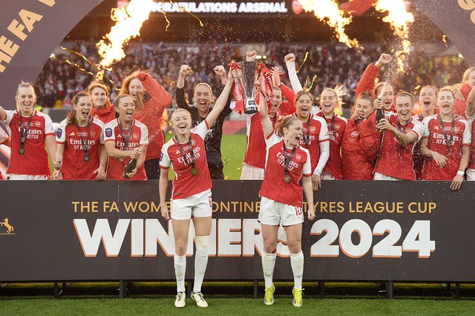 Arsenal's Leah Williamson, centre left, and Kim Little lift the trophy after winning the FA Women's Continental Tyres League Cup Final at Molineux Stadium, Wolverhampton, England, Sunday March 31, 2024. (Nick Potts/PA via AP)