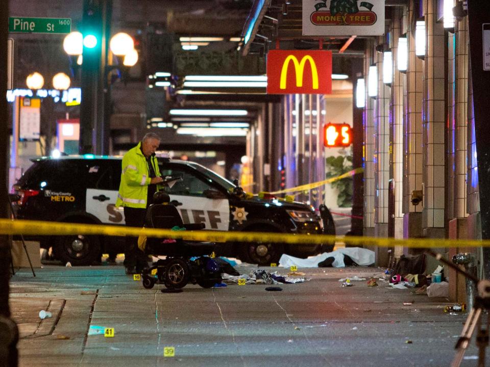 A crime-scene investigator inspects the scene of a shooting that left one person dead and seven injured, including a child, in downtown Seattle: AFP via Getty Images