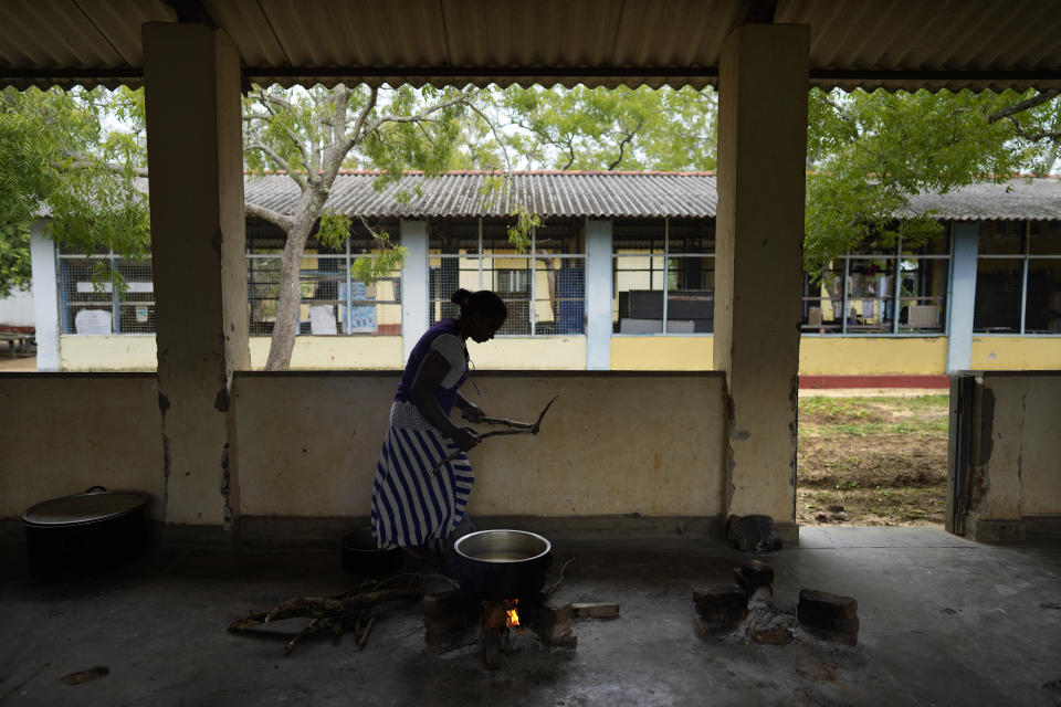 A parent of Dalukana Primary School boils a pot of fresh milk using a firewood hearth before giving it away to students in Dimbulagala, about 200 kilometres north east of Colombo, Sri Lanka, Monday, Dec. 12, 2022. Due to Sri Lanka's current economic crisis in Dimbulagala primary school children receive a free breakfast, a glass of milk and lunch with help from the education ministry, WFP and a private donor agency. Mothers of students prepare the meals at school with the menu provided by the education ministry. Each meal costs $0.27. (AP Photo/Eranga Jayawardena)