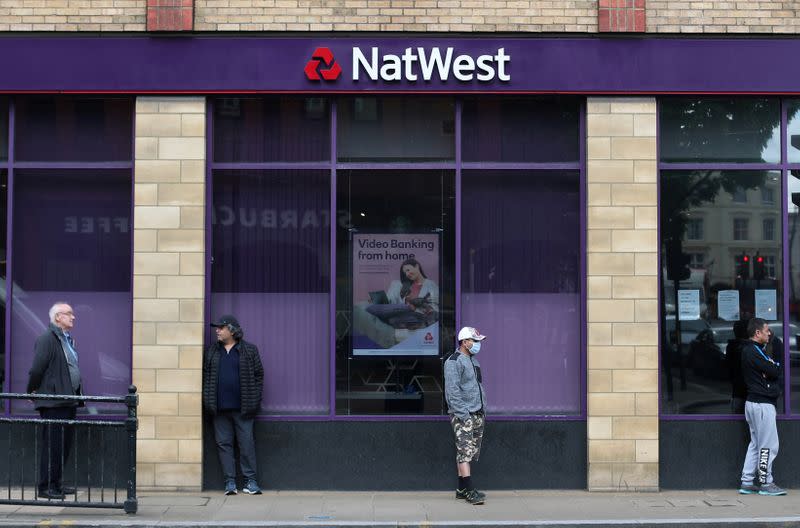 FILE PHOTO: People maintain social distance while they queue outside a Natwest bank in Wimbledon