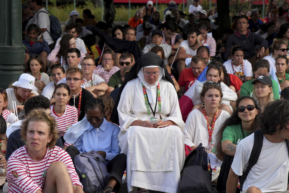 Pilgrims sit down during the opening mass of World Youth Day, attended by several tens of thousands, at Eduardo VII park in central Lisbon, Tuesday, Aug. 1, 2023. Pope Francis will arrive Aug. 2 to attend the event that is expected to bring hundreds of thousands of young Catholic faithful to Lisbon and finishes Aug. 6. (AP Photo/Ana Brigida)