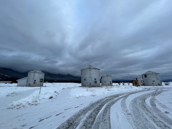 Five grain silos are seen in a snowy field in Montana.