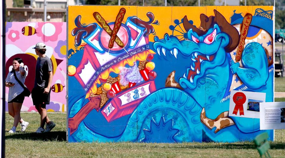 People walk by a mural painted by Caitlyn Shepherd during the 2022 Oklahoma State Fair.