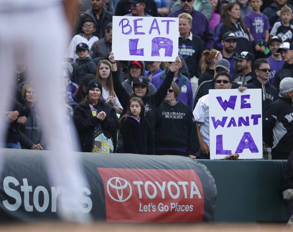 Fans hold up signs in the ninth inning of a baseball game as the Colorado Rockies host the Washington Nationals Sunday, Sept. 30, 2018, in Denver. The Rockies won 12-0 and advance to a playoff game for the National League Western Division title against the Los Angeles Dodgers. (AP Photo/David Zalubowski)