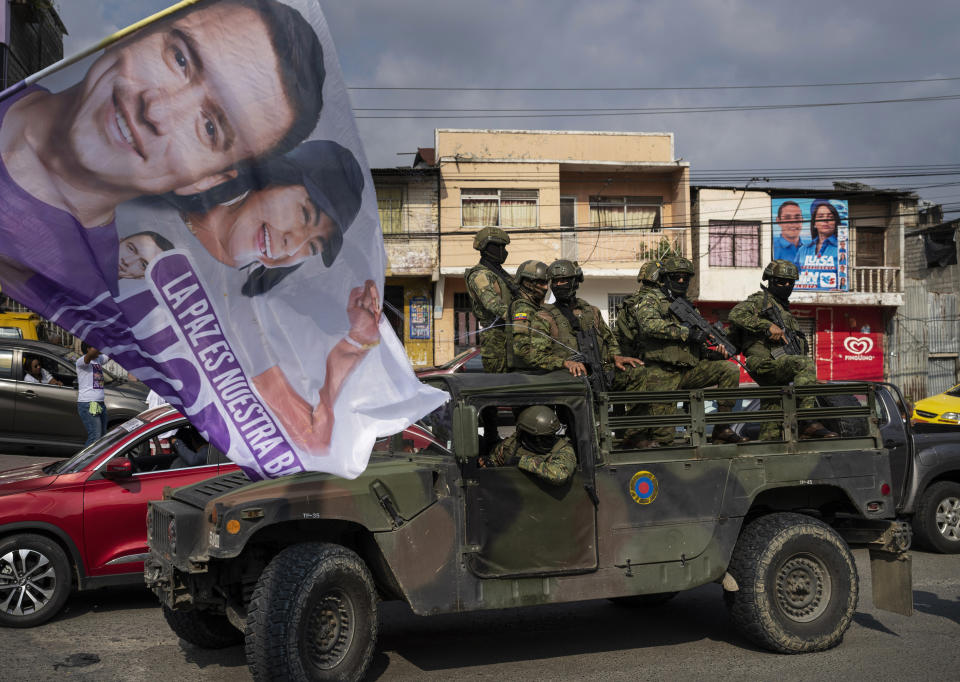 Soldiers stand guard on top of an armored vehicle as supporters of presidential candidate Daniel Noboa, of the National Democratic Action Alliance political party, attend a rally downtown in Esmeraldas, Ecuador, Friday, Oct. 6, 2023. Ecuador will hold a presidential runoff, Oct. 15. (AP Photo/Rodrigo Abd)