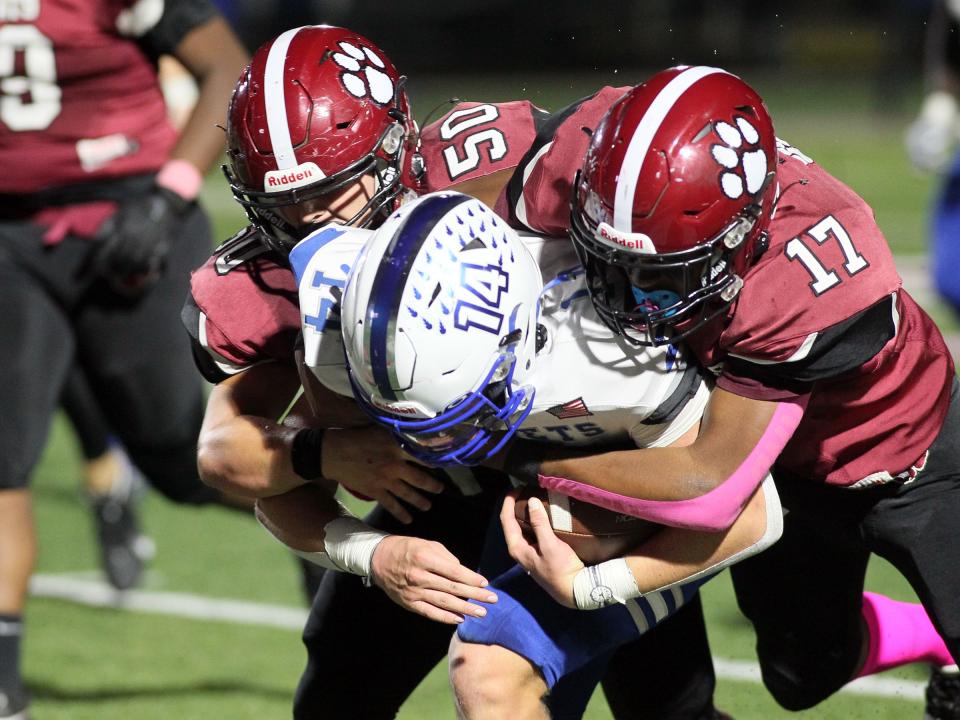 Newark's Jack Kopachy (50) and Alex Irvin-Royster combine for a tackle against Central Crossing on Friday.
