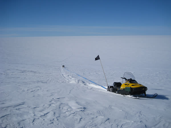 On a rare clear day, a snowmobile is stuck in soft snow.