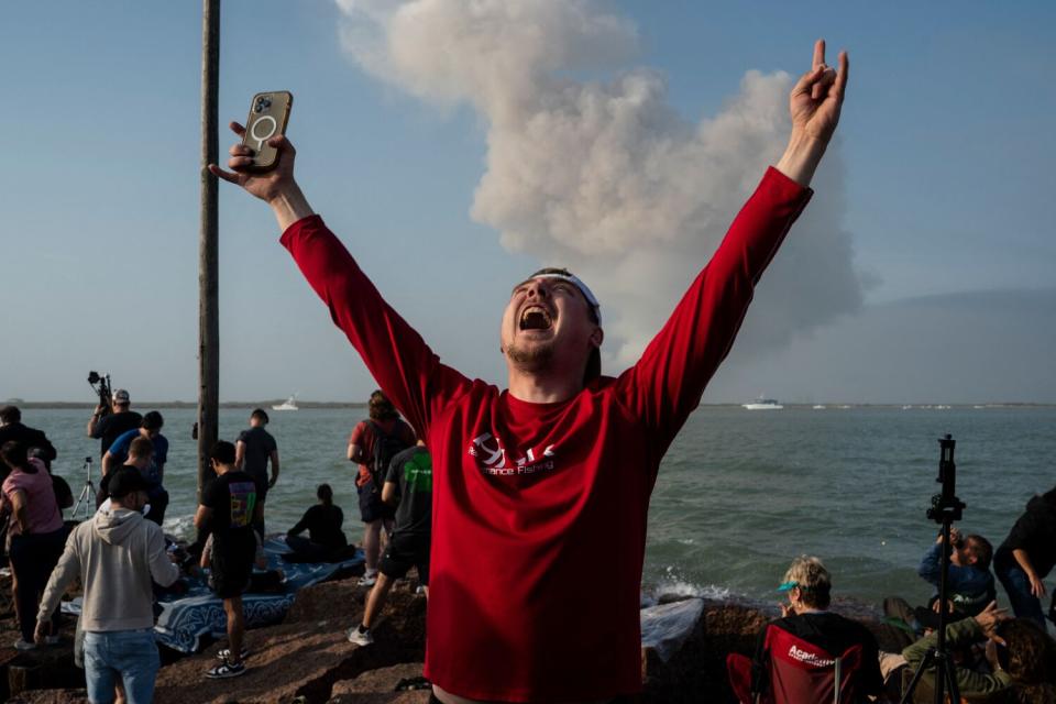 A spectator raises their arms as they celebrate SpaceX Starship launch