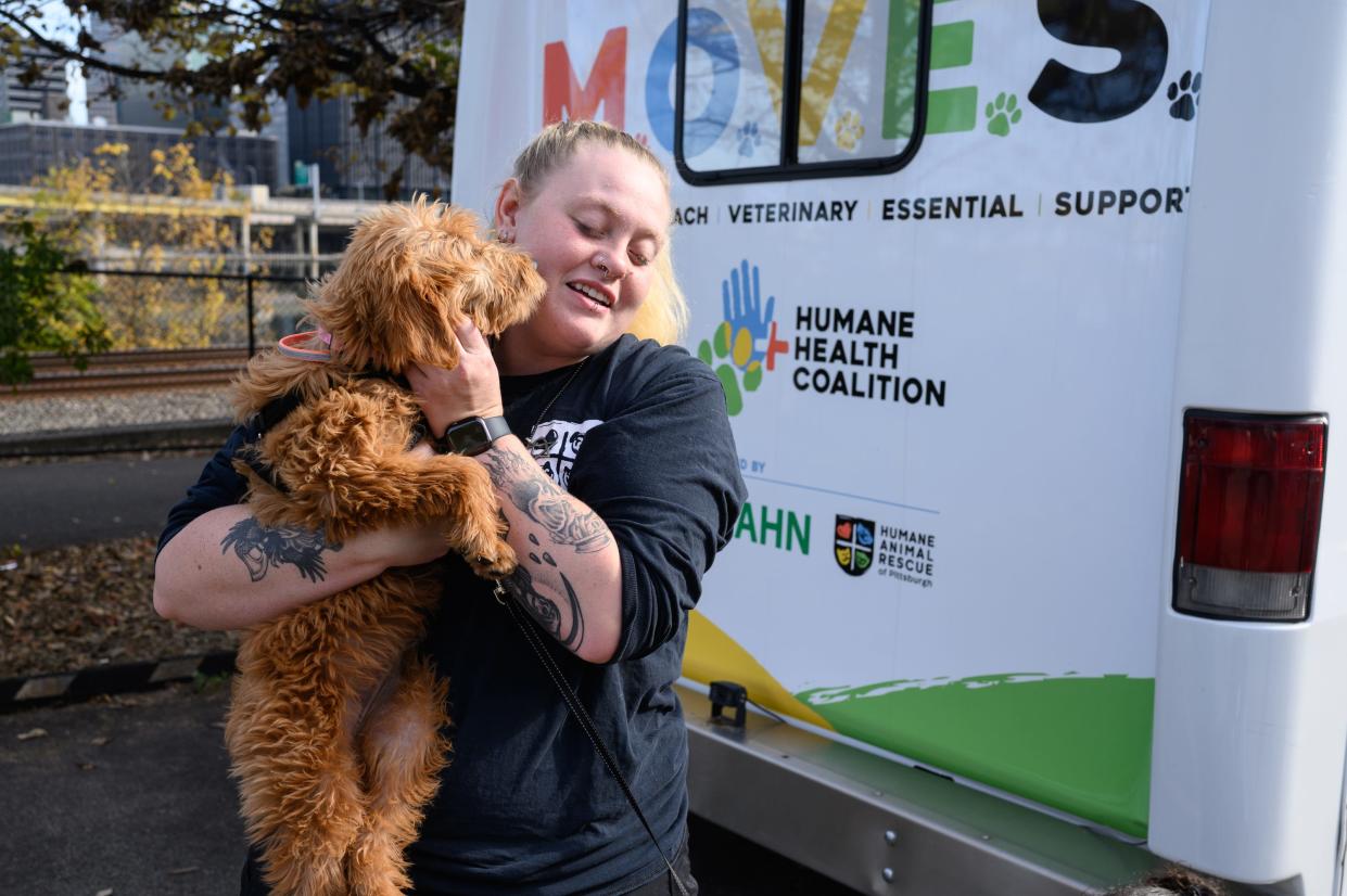 Brianna Kaufman, 27, assistant director of medical services at the Humane Animal Rescue of Pittsburgh, holds a dog outside a mobile clinic for pets and their people on Oct. 26 in Pittsburgh.