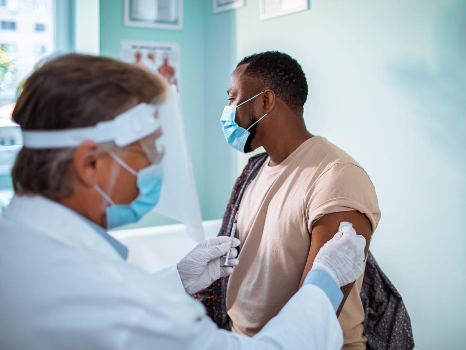 Black, male patient gets a shot in the doctor's office.