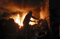 People try to remove car tyres from a car shop on fire after shelling by Azerbaijan's artillery during a military conflict in Stepanakert, the separatist region of Nagorno-Karabakh, Friday, Oct. 23, 2020. Heavy fighting raged Friday over Nagorno-Karabakh even as top diplomats from Armenia and Azerbaijan visited Washington for negotiations on settling the neighboring countries' decades-long conflict. (AP Photo)