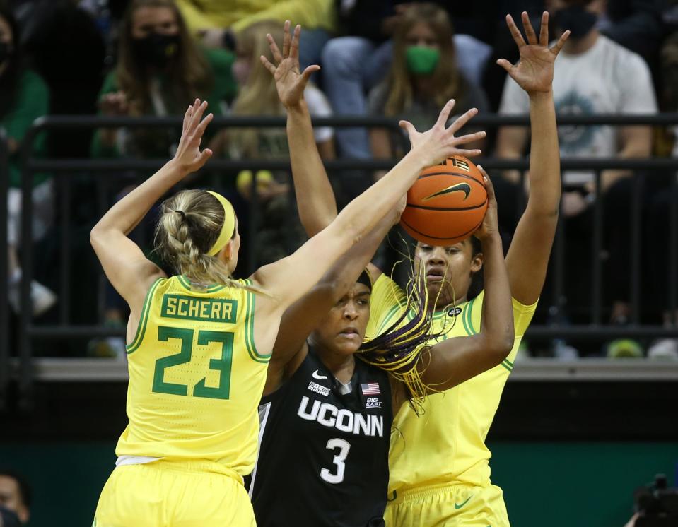 Oregon's Maddie Scherr, left, and Nyara Sabally, right, cover UConn's Aaliyah Edwards under the basket during the second half Jan. 17, 2022.