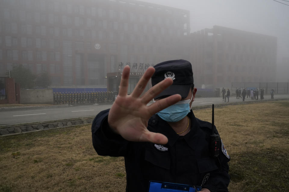 FILE - A security person moves journalists away from the Wuhan Institute of Virology after a World Health Organization team arrived for a field visit in Wuhan in China's Hubei province on Feb. 3, 2021. The hunt for COVID-19 origins has gone dark in China. An AP investigation drawing on thousands of pages of undisclosed emails and documents and dozens of interviews found feuding officials and fear of blame ended meaningful Chinese and international efforts to trace the virus almost as soon as they began, despite years of public statements to the contrary. (AP Photo/Ng Han Guan, File)