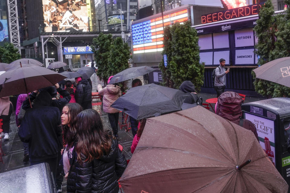 Pedestrians take cover under umbrellas as they walk through a wet Times Square in New York, Monday, Dec. 18, 2023. A storm moving up the East Coast brought heavy rain and high winds to the Northeast on Monday, threatening flooding, knocking out power to hundreds of thousands, and forcing flight cancelations and school closings. (AP Photo/Seth Wenig)