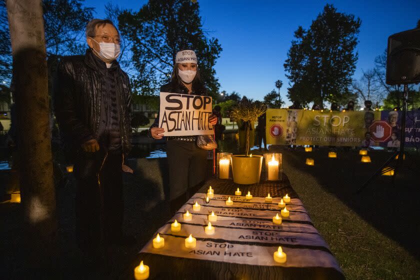 GARDEN GROVE, CA - March 23: Vanessa Nguyen, center, of Irvine, holds a Stop Asian Hate sign while joining community leaders praying, displaying and delivering messages of peace during a candlelight vigil mourning the victims of the Atlanta killings at Community Center Park Tuesday, March 23, 2021 in Garden Grove, CA. (Allen J. Schaben / Los Angeles Times)