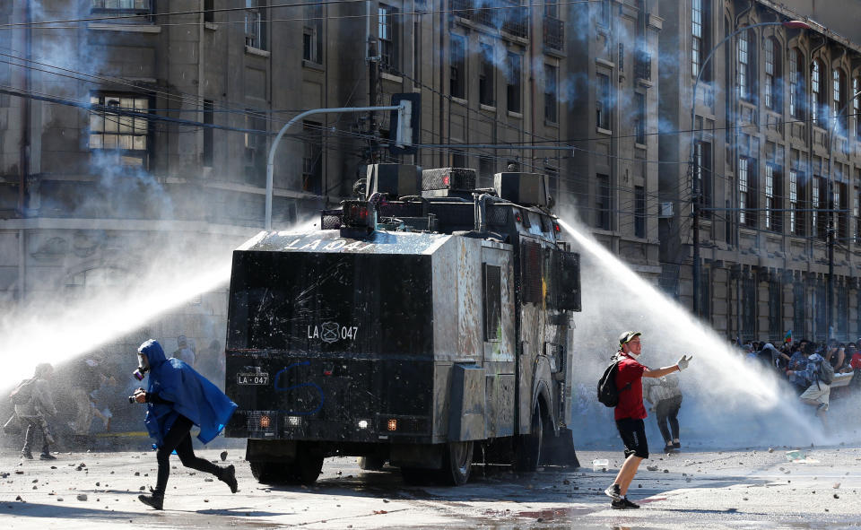 People walk away as riot police use a water cannon during a protest against Chile's government in Valparaiso, Chile on Oct. 28, 2019. (Photo: Rodrigo Garrido/Reuters)