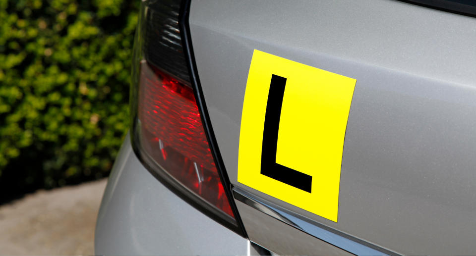 L plate on back of silver car. 