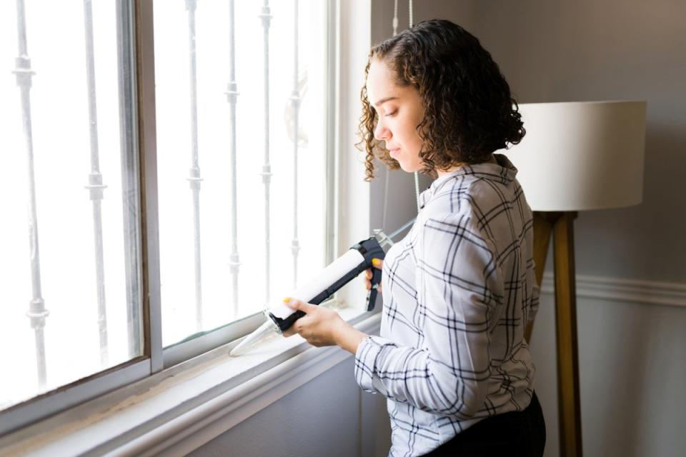 Woman sealing windows.