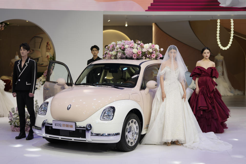 Models in wedding gowns showcase the Ora Funky Cat EV car model by Great Wall Motor during the Auto Shanghai 2023 at the National Exhibition and Convention Center in Shanghai, China, Tuesday, April 18, 2023. Global and Chinese automakers plan to unveil more than a dozen new electric SUVs, sedans and muscle cars this week at the Shanghai auto show, their first full-scale sales event in four years in a market that has become a workshop for developing electrics, self-driving cars and other technology.