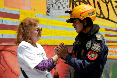 A woman thanks a rescue worker after a minute of silence at the Tlalpan housing project, affected by the September 2017 earthquake, in Mexico City, Mexico September 19, 2018. REUTERS/Daniel Becerril