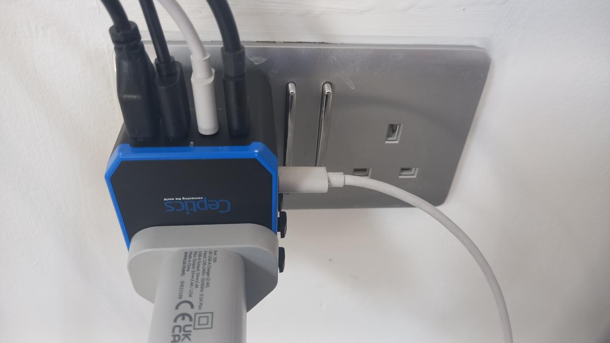  Ceptics 70W World Travel Plug Adapter plugged into socket with five USB leads and a UK plug attached. 