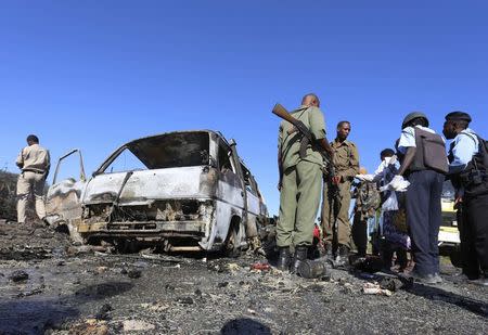 Somali government soldiers stand around the wreckage after a suicide car bomb explosion targeting peacekeeping troops in a convoy outside the capital Mogadishu September 8, 2014. REUTERS/Feisal Omar