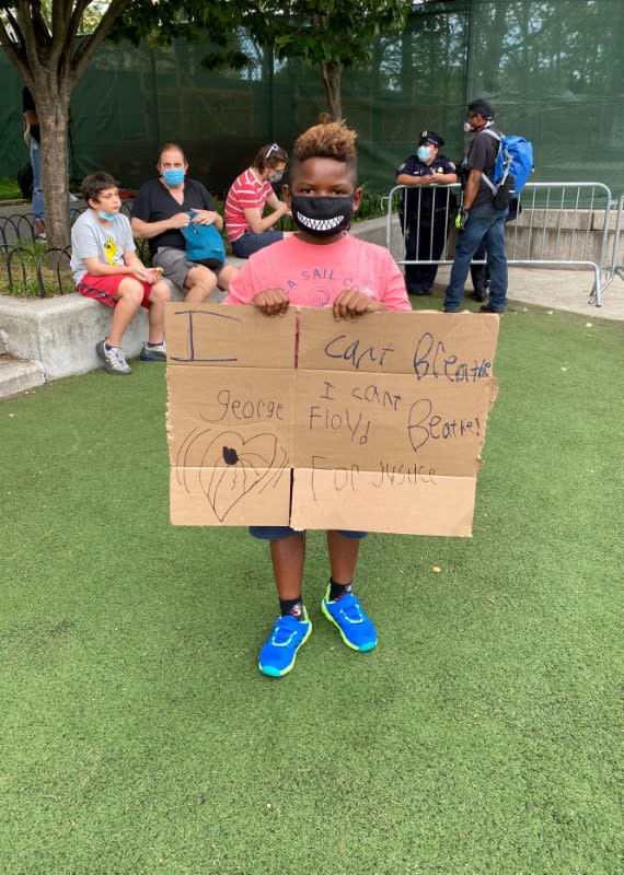 Ellis holds a sign he made as he attends a memorial in Brooklyn's Cadman Plaza Park for George Floyd