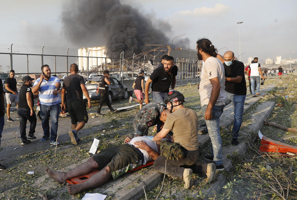 FILE - In this Tuesday, Aug. 4, 2020 file photo, rescue workers help an injured man at the explosion scene that hit the seaport of Beirut, Lebanon. It was 20 minutes before 6:08 p.m. when the Beirut fire brigade received the call from an employee at the nearby port reporting a big fire. Ten firefighters, including a female paramedic, piled into a fire engine and an ambulance and raced toward the scene, and their ultimate death. (AP Photo/Hussein Malla, File)