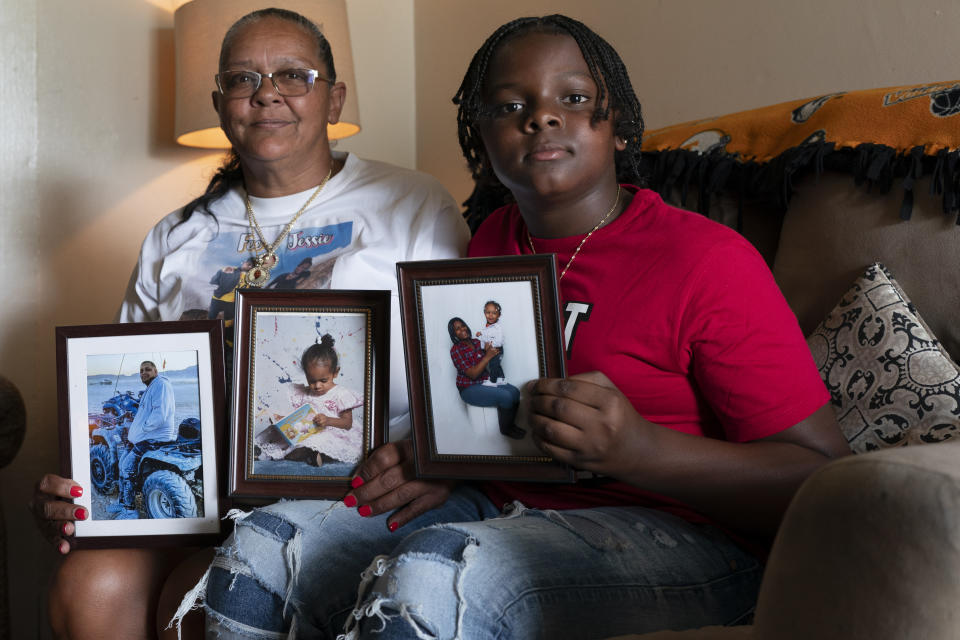 Charlene Roberts and her grandson Princeton Roberts, 11, pose with portraits of her son Kevin and daughter Jessie on Friday, Aug. 4, 2023, in Knoxville, Tenn. Roberts' son, Kevin, was killed in 2021 and her daughter, Jessie, in 2019. Knoxville saw a surge in fatal shootings during the beginning of the pandemic, and community leaders are working on a new effort to reduce gun violence. (AP Photo/George Walker IV)