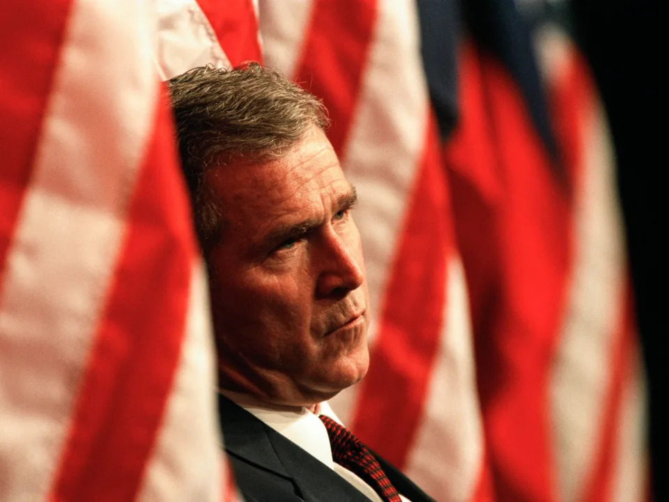 Then-Texas Gov. George W. Bush standing between American flags in 1999.