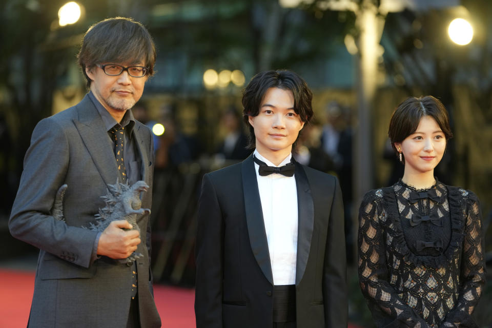 El director de "Godzilla Minus One", Takashi Yamazaki, de izquierda a derecha, y los actores Ryunosuke Kamiki y Minami Hamabe posan en la alfombra roja antes de la ceremonia inaugural de la 36a edición del Festival Internacional de Cine de Tokio en Tokio, Japón el 23 de octubre de 2023. (Foto AP/Shuji Kajiyama)