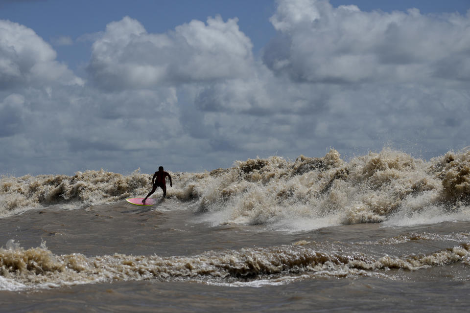 El surfista brasileño Naysson Costa cabalga unas olas llamadas "Pororoca" durante el festival de surf amazónico celebrado en el Canal do Perigoso, en la desembocadura del río Amazonas cerca de Chaves, en el archipiélago de las Islas Marajo, en el estado de Pará, Brasil, el 5 de junio de 2023. (AP Foto/Eraldo Peres)